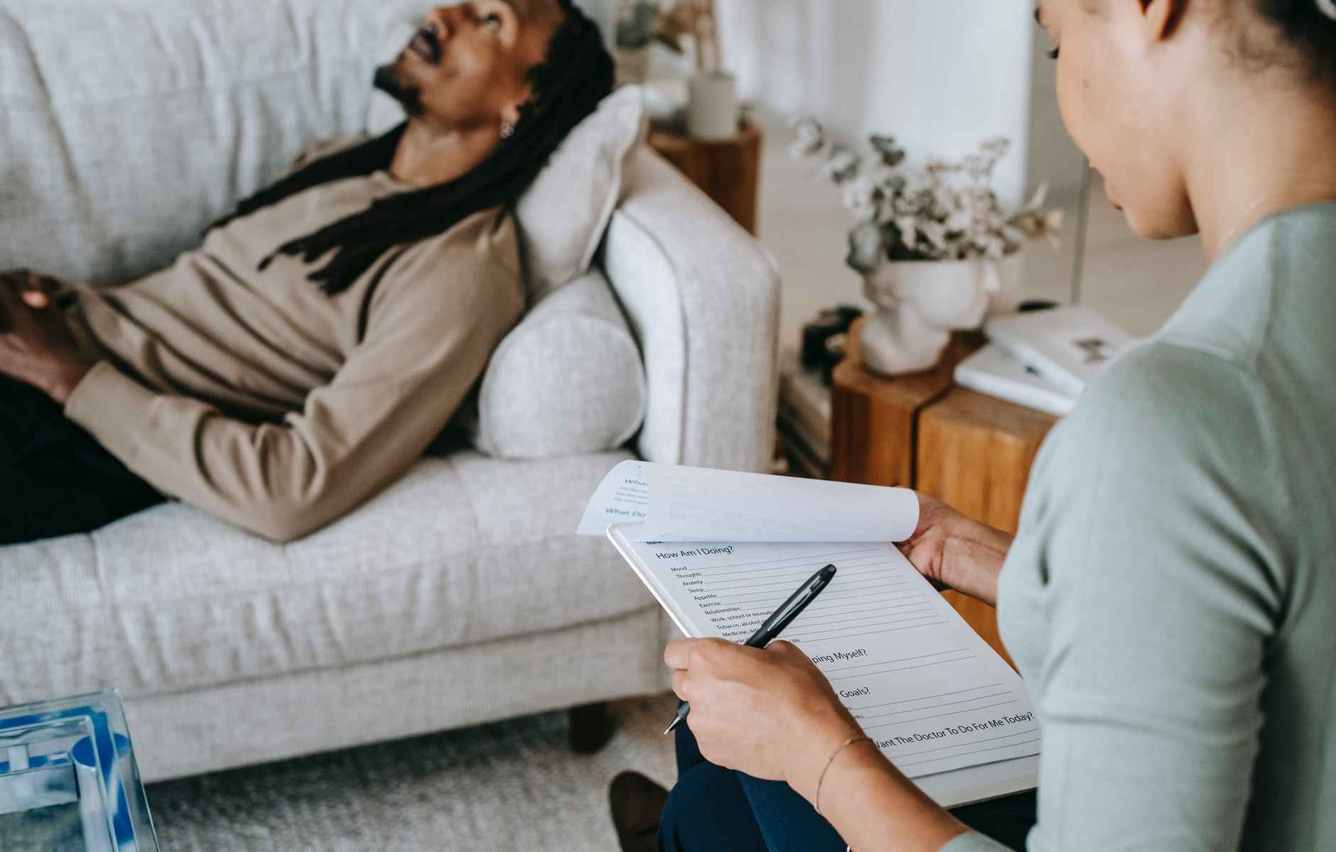 crop black woman with questionnaire interacting with boyfriend on couch